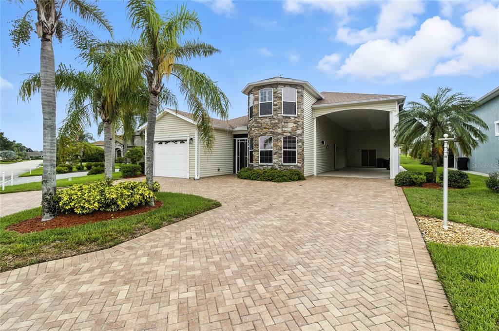 A single-story house with a stone-accented turret, a paved driveway, and a covered carport — 529 MEANDERING WAY, POLK CITY, FL