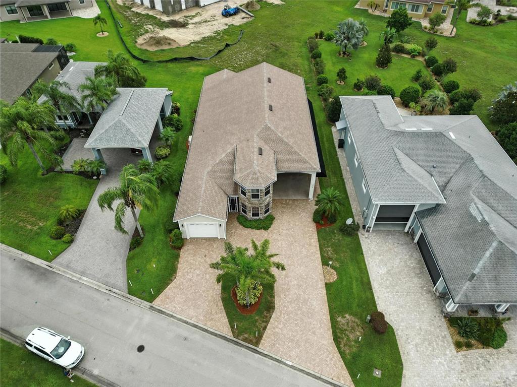 An aerial view shows a house with a paver driveway, a palm tree, and neighboring homes — 529 MEANDERING WAY, POLK CITY, FL