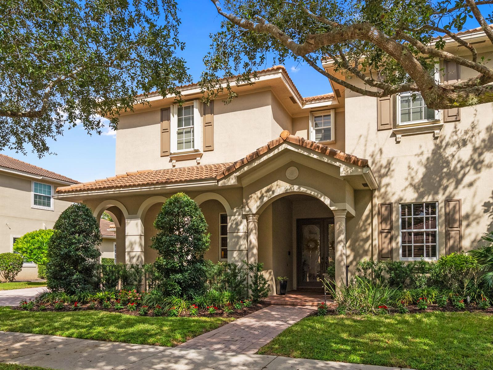 A two-story beige stucco house with a tiled roof, arched entryway, and landscaped front yard — 175 Via Rosina, Jupiter FL 33458, JUPITER, FL
