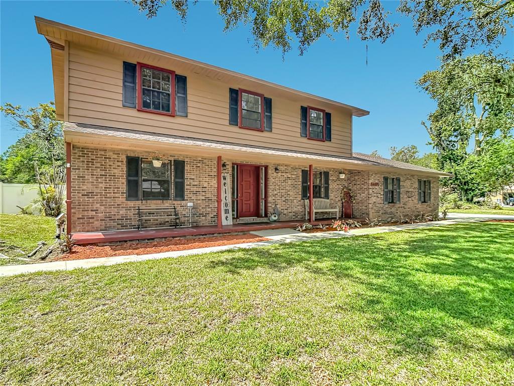 A two-story house with a brick lower level, tan siding upper level, and red front door — 3465 JAMIE STREET, MULBERRY, FL