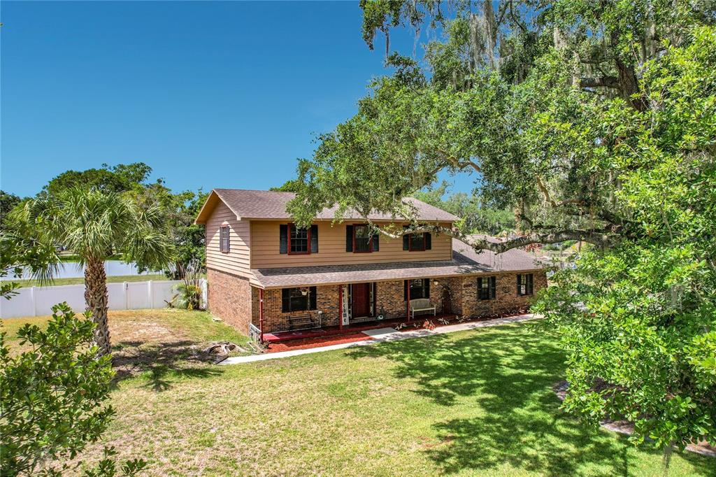 A two-story house with a brick lower level and tan siding sits on a grassy lot — 3465 JAMIE STREET, MULBERRY, FL