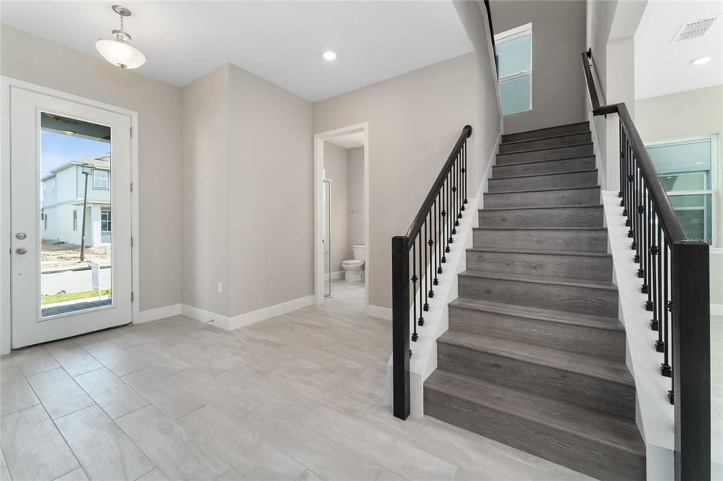 An entryway features light tile flooring, a staircase with dark wood treads, and a powder room — 13254 MCMILLAN DRIVE, ORLANDO, FL