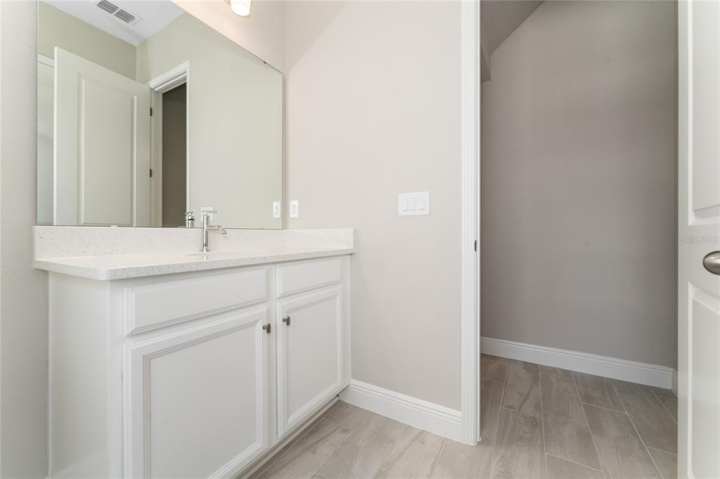 A bathroom features a white vanity with a stone countertop, large mirror, and tiled floor — 13254 MCMILLAN DRIVE, ORLANDO, FL