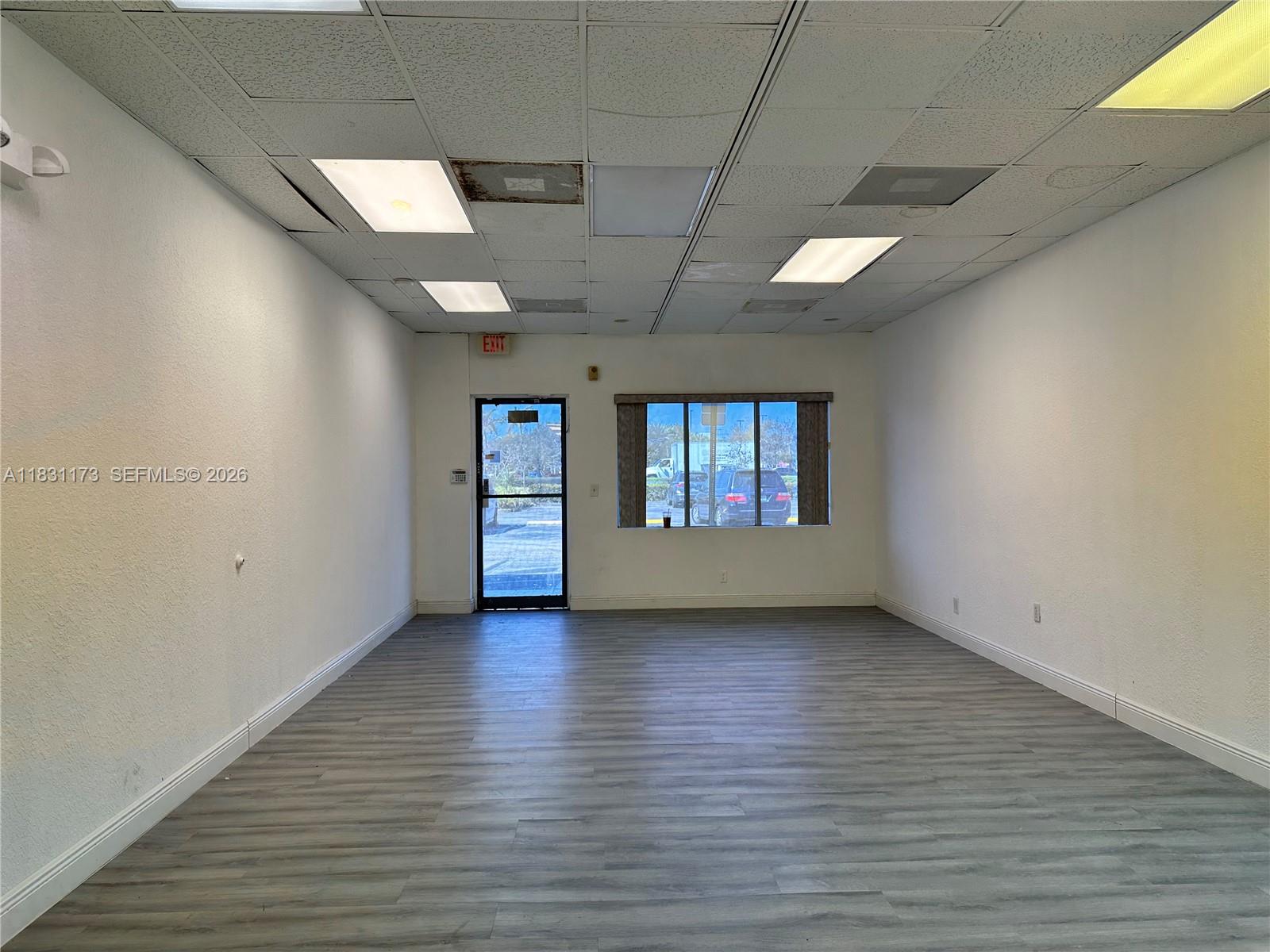 An empty commercial space features white walls, gray wood-look flooring, and a drop ceiling — 2922 N State Road 7 # 2916, Margate FL 33063, MARGATE, FL