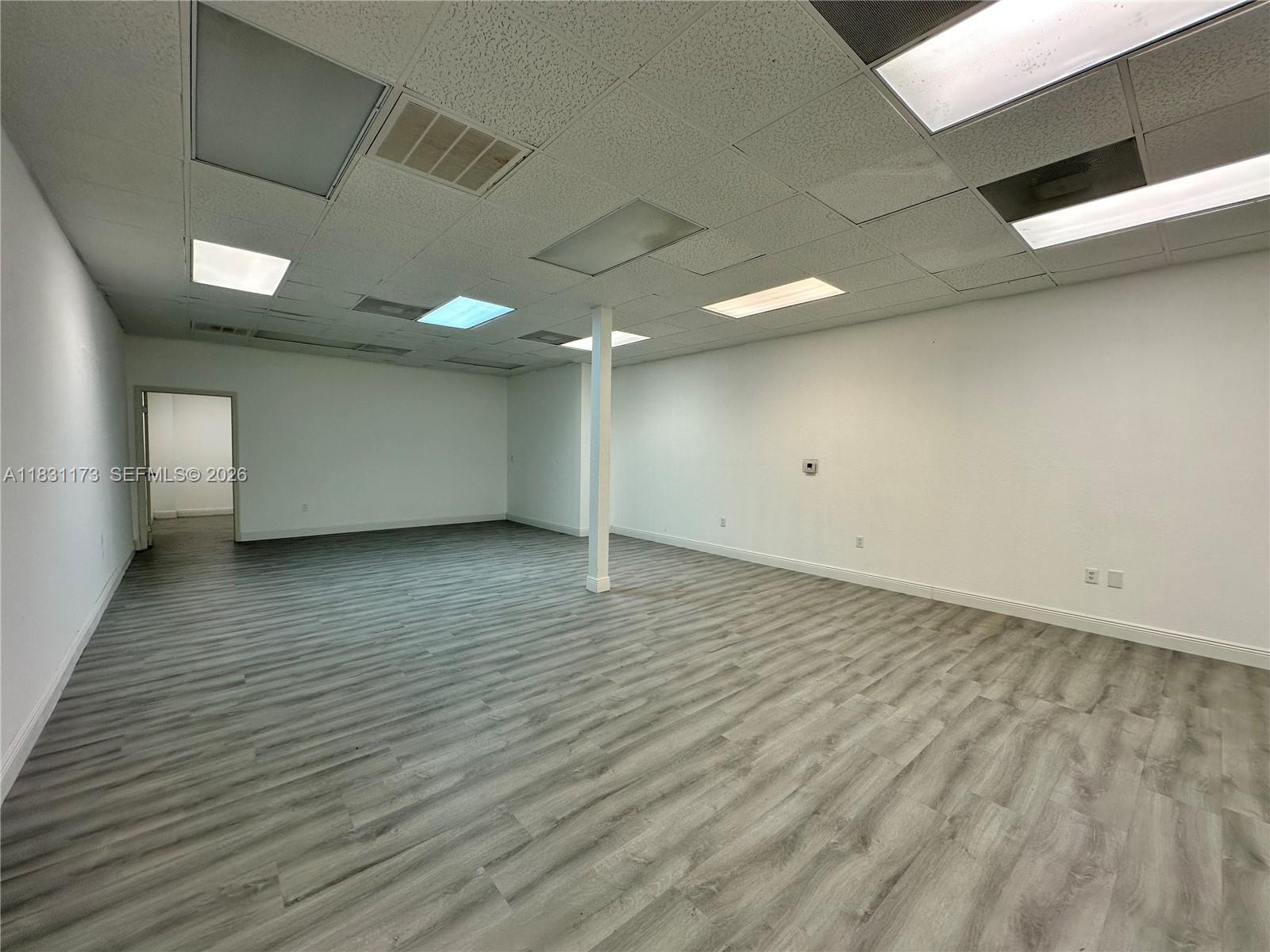 An empty office space features white walls, a drop ceiling with recessed lighting, and wood-look flooring — 2922 N State Road 7 # 2916, Margate FL 33063, MARGATE, FL