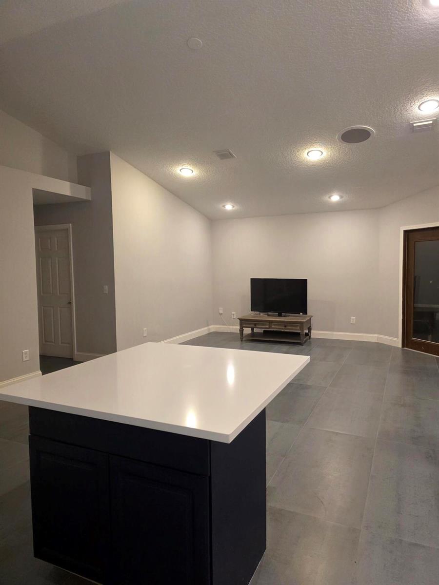 A kitchen island with a white countertop sits in front of a living area — 5852 Eagle Cay Terrace, Coconut Creek FL 33073, COCONUT CREEK, FL