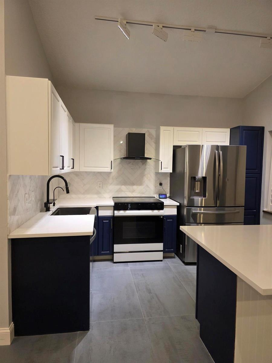 A kitchen features white upper cabinets, navy lower cabinets, white countertops, and stainless steel appliances — 5852 Eagle Cay Terrace, Coconut Creek FL 33073, COCONUT CREEK, FL