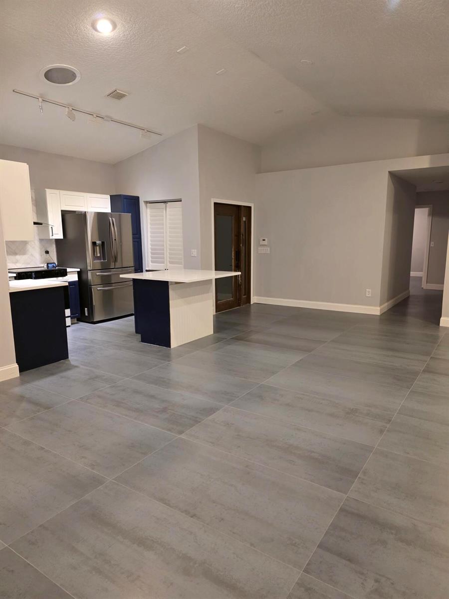 A kitchen with blue and white cabinetry, a small island, and large gray floor tiles — 5852 Eagle Cay Terrace, Coconut Creek FL 33073, COCONUT CREEK, FL