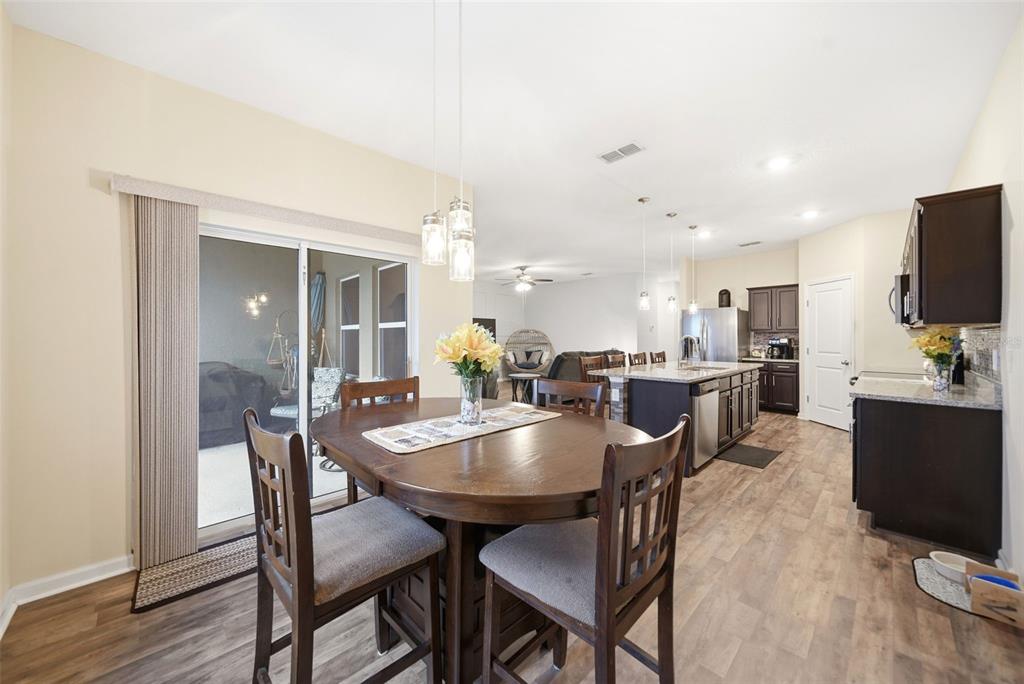 A dining area with a wooden table and chairs opens into a kitchen with an island — 1151 LYCASTE DRIVE, DAVENPORT, FL