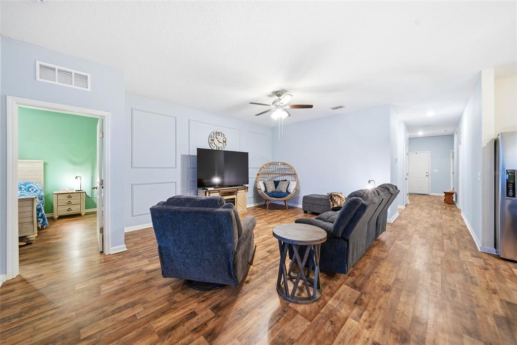 A living room features light blue walls, wood-look flooring, a ceiling fan, and gray furniture — 1151 LYCASTE DRIVE, DAVENPORT, FL
