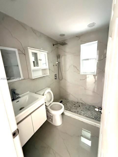 A modern bathroom features marble-patterned walls, a white vanity, a toilet, and a walk-in shower — 760 SE 7th Ave # 760, Hialeah FL 33010, HIALEAH, FL