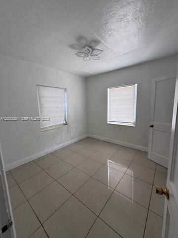 An empty bedroom features light-colored tile flooring, white walls, two windows, and a ceiling light — 760 SE 7th Ave # 760, Hialeah FL 33010, HIALEAH, FL