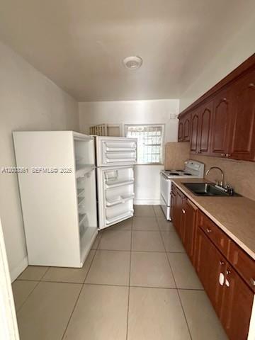 A kitchen features a white refrigerator, wooden cabinets, a sink, and light-colored tile flooring — 760 SE 7th Ave # 760, Hialeah FL 33010, HIALEAH, FL