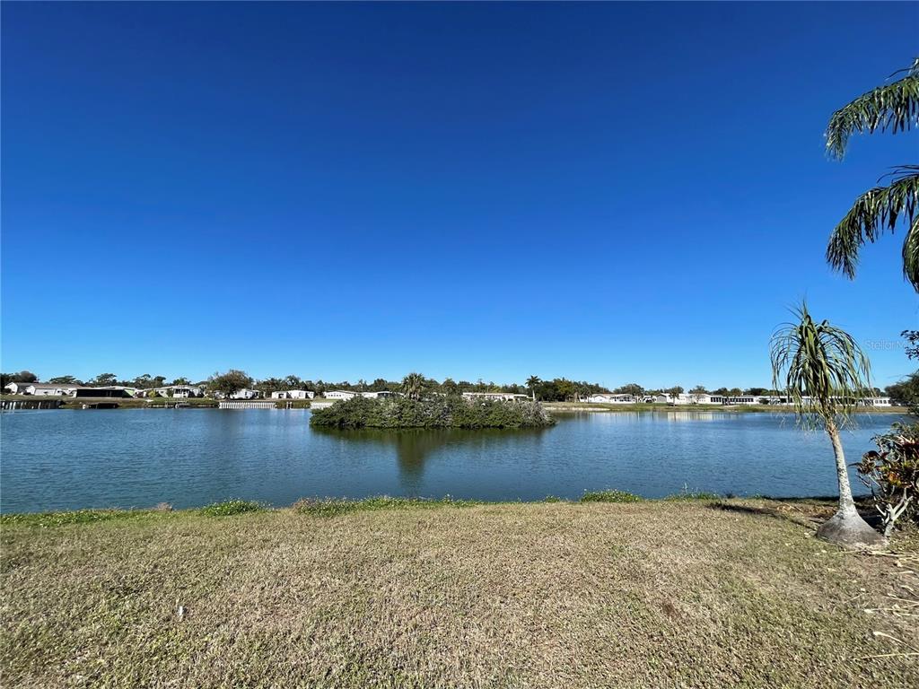 A view of a lake with a small island and houses in the distance — 1303 SANDERLING DRIVE, ENGLEWOOD, FL
