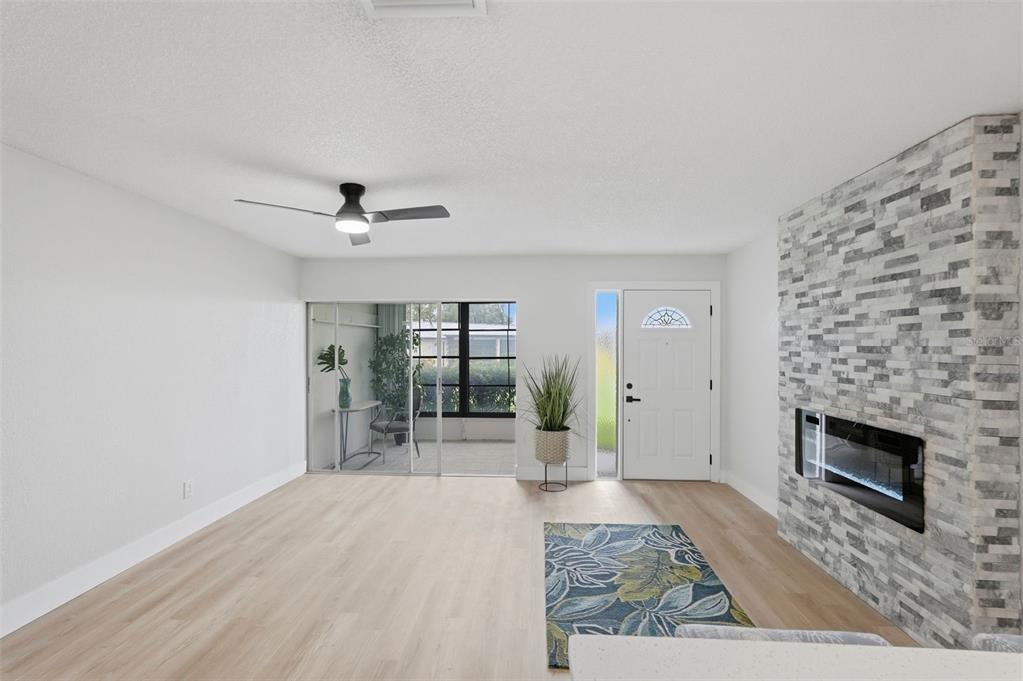 A living room features light wood flooring, a stone fireplace, and a sliding glass door — 1339 QUEEN ANNE DRIVE UNIT C, PALM HARBOR, FL