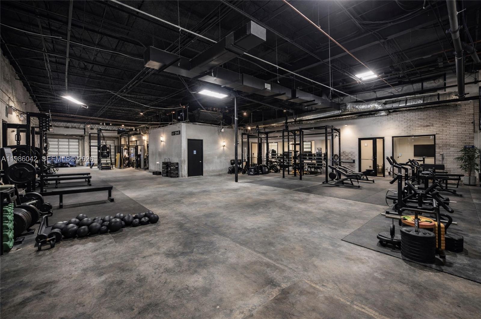 An industrial-style gym features exposed ceilings, concrete floors, and various weightlifting equipment — 2950 N 28th Ter, Hollywood FL 33020, HOLLYWOOD, FL