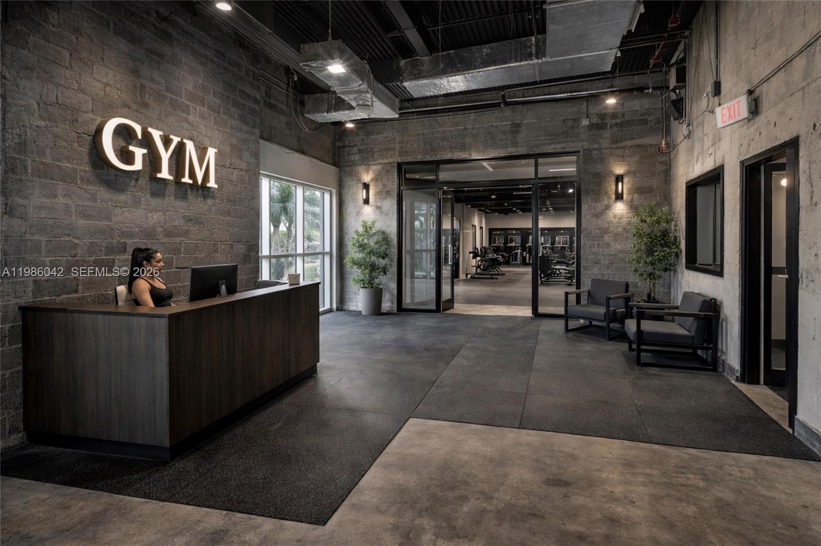 A gym reception area features a dark wood desk, concrete walls, and glass entry doors — 2950 N 28th Ter, Hollywood FL 33020, HOLLYWOOD, FL