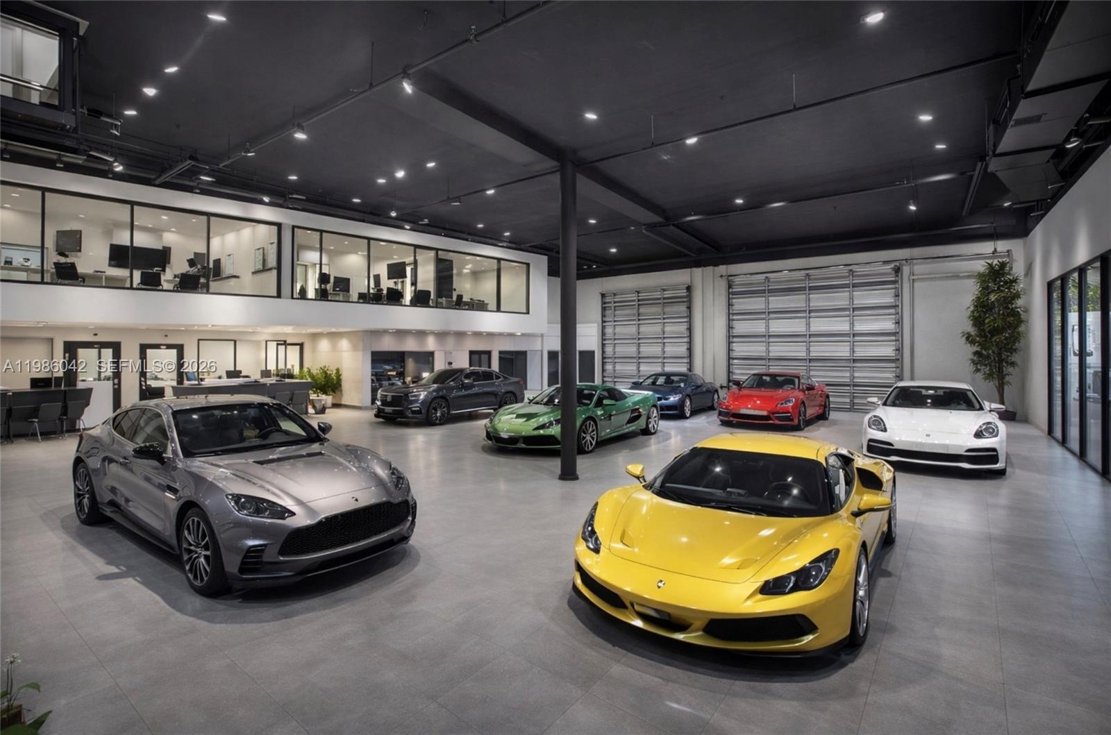 A modern, spacious car showroom features a polished gray floor, black ceiling, and multiple luxury vehicles — 2950 N 28th Ter, Hollywood FL 33020, HOLLYWOOD, FL
