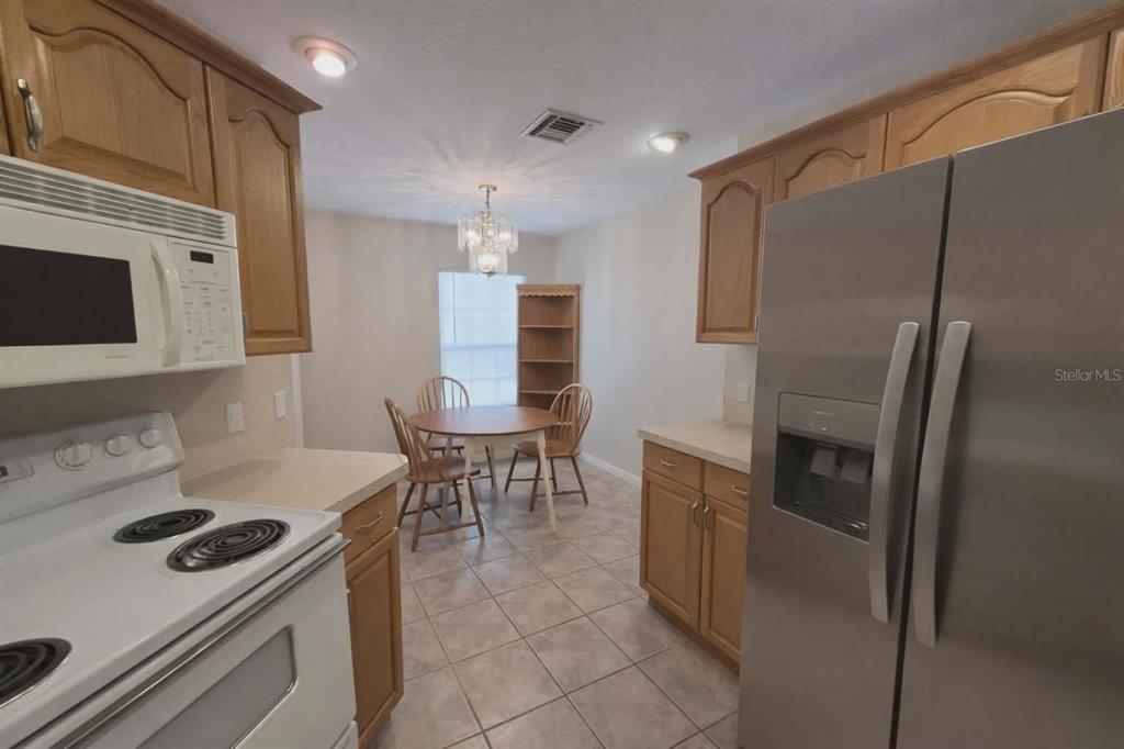 A kitchen with light wood cabinets, white appliances, and a dining area with a table — 14396 SW 19TH PLACE, OCALA, FL