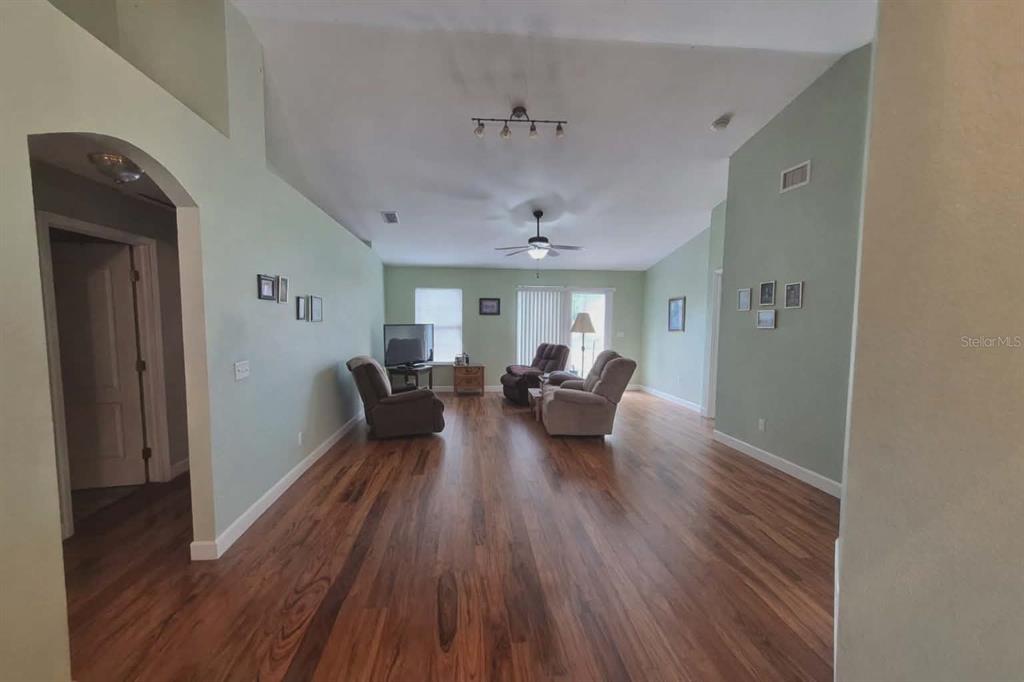 A living room with light green walls, wood flooring, and a vaulted ceiling — 14396 SW 19TH PLACE, OCALA, FL