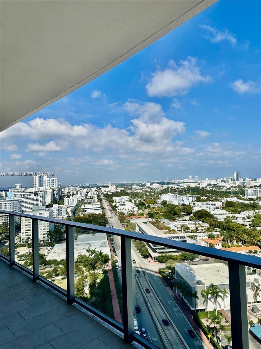 A high-angle view from a balcony overlooking a city street, buildings, and a blue sky — 500 ALTON RD # 1708, Miami Beach FL 33139, MIAMI BEACH, FL