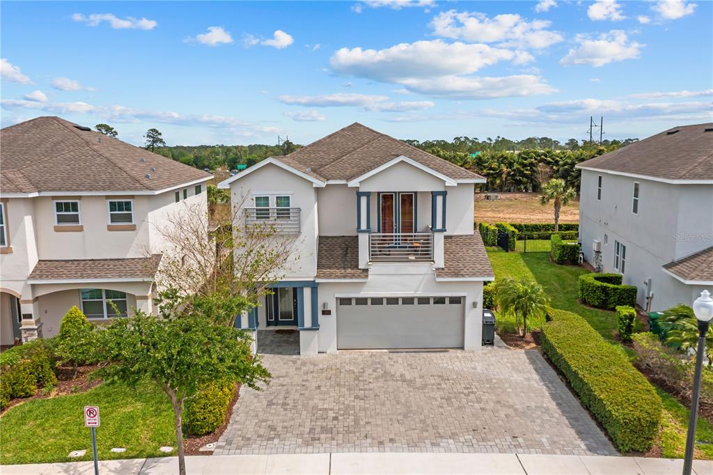 An exterior view of a two-story suburban house with a paved driveway and balcony — 7483 MARKER AVENUE, KISSIMMEE, FL