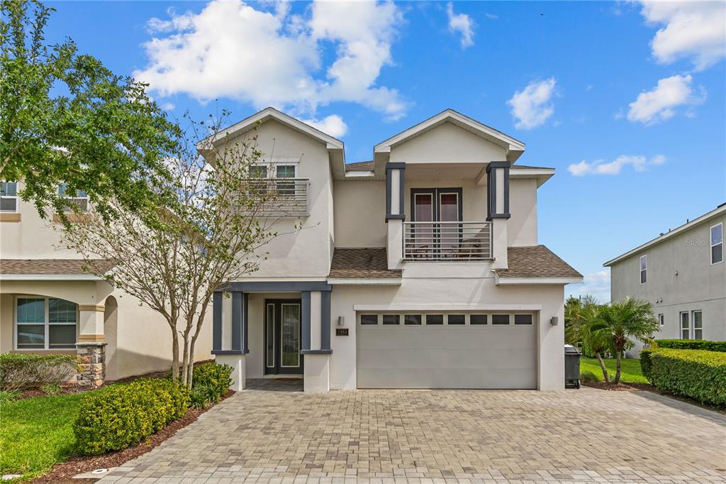 A two-story house with a paved driveway, a two-car garage, and two upper-level balconies — 7483 MARKER AVENUE, KISSIMMEE, FL