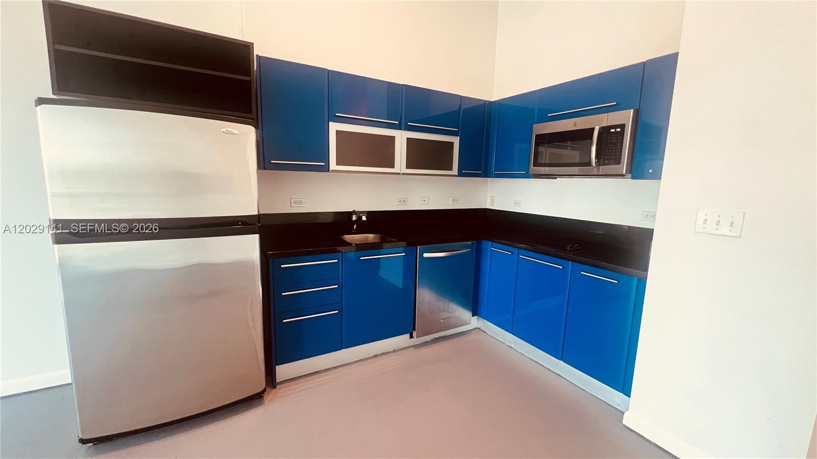 A kitchen features blue cabinets, stainless steel appliances, and a black countertop — 253 NE 2nd St # 330, Miami FL 33132, MIAMI, FL