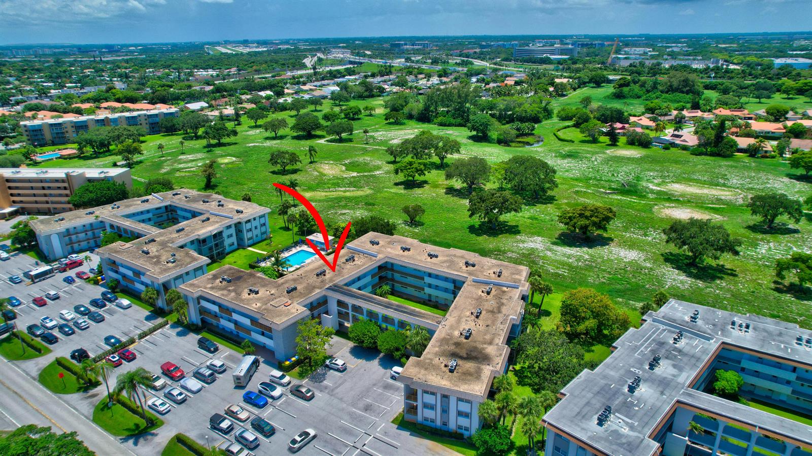 An aerial view of a multi-story apartment complex with a swimming pool and parking lot — 5501 NW 2nd Avenue # 313, Boca Raton FL 33487, BOCA RATON, FL