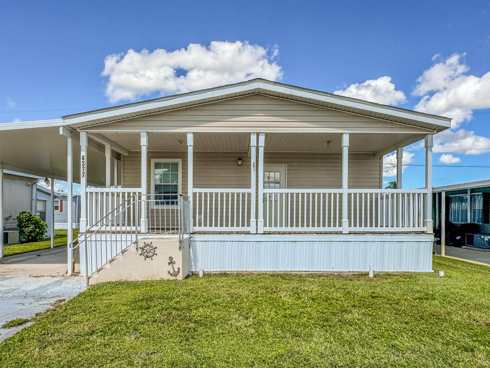 A beige mobile home features a covered front porch with white railings and stairs — 4377 Mission Bell Drive, Boynton Beach FL 33436, BOYNTON BEACH, FL