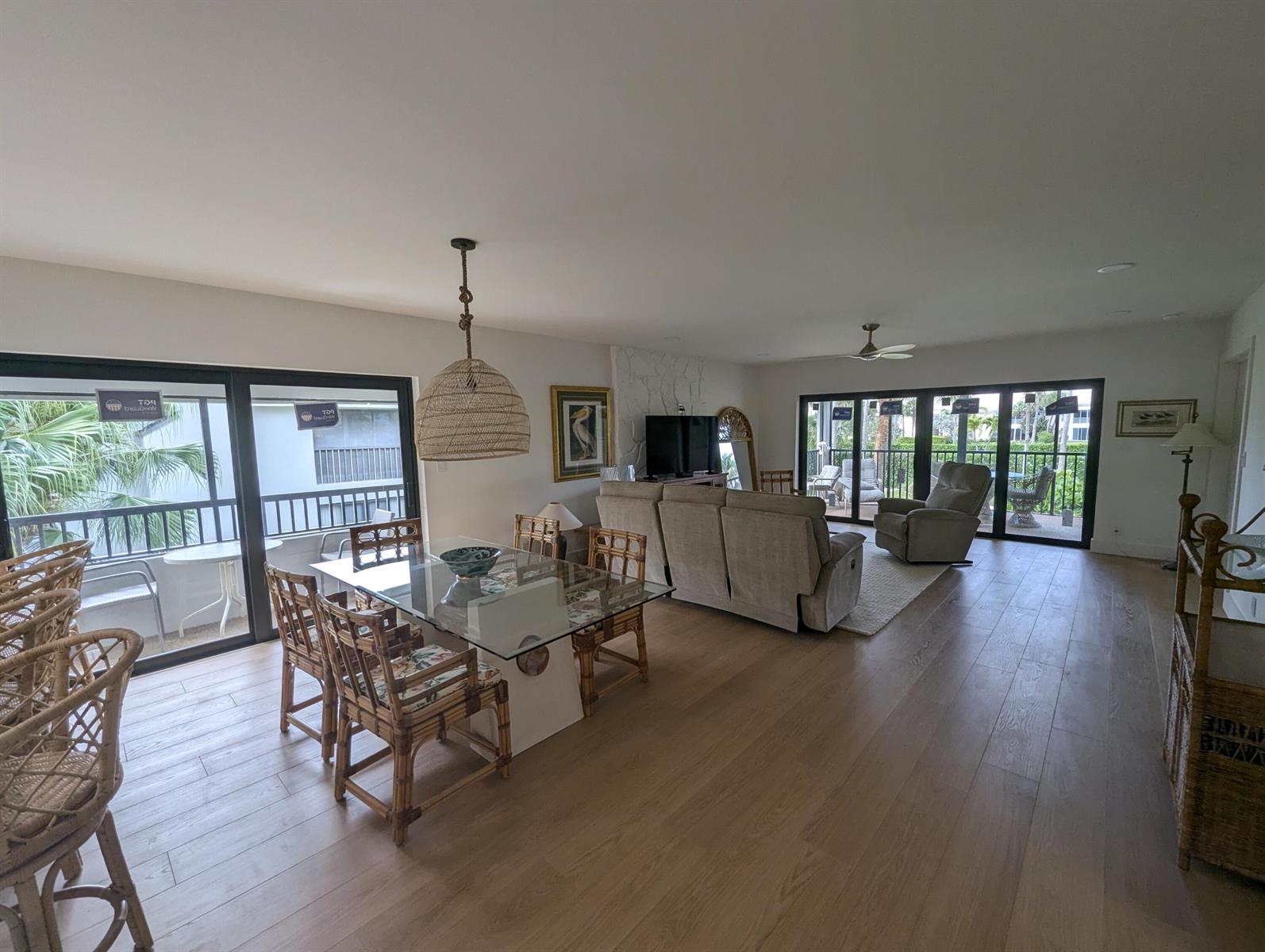 An open-concept living and dining area features light wood flooring, rattan furniture, and sliding glass doors — 404 Clubhouse Circle, Jupiter FL 33477, JUPITER, FL