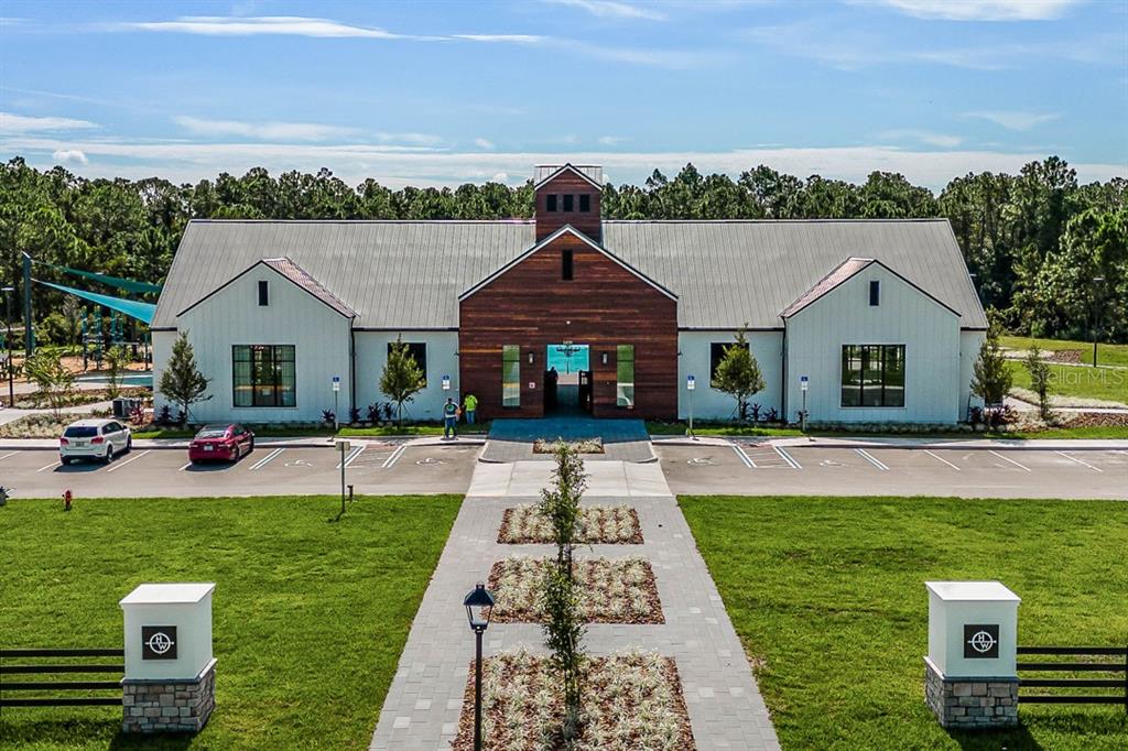 A modern community center building with a wood-paneled entrance and a large parking lot — 7110 SANDHILL CRANE WAY UNIT 1, ST CLOUD, FL