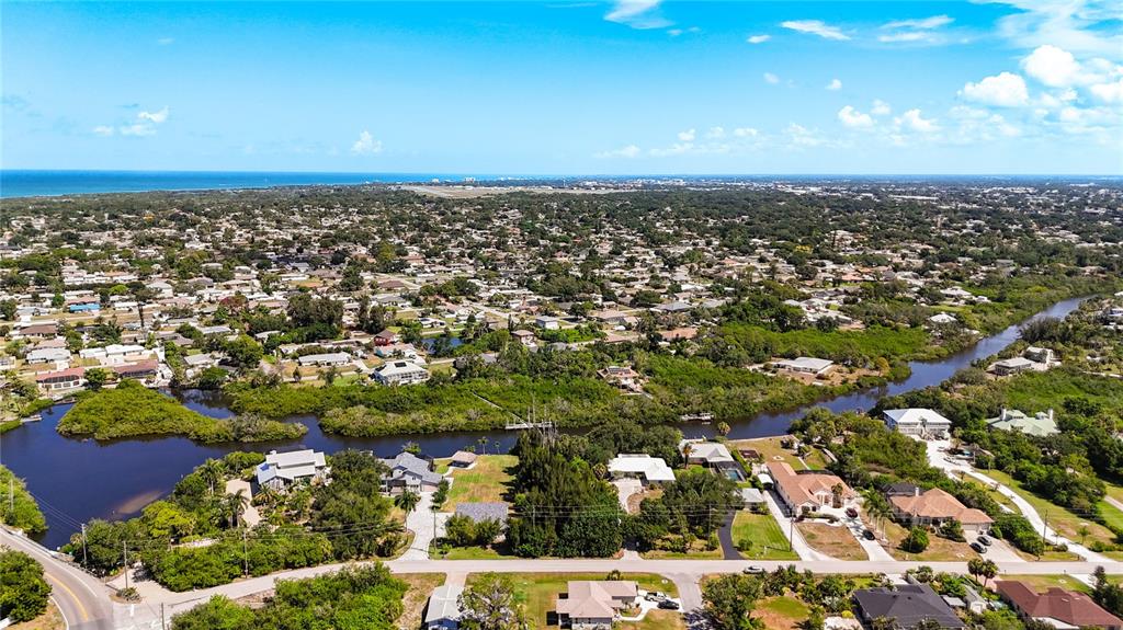 An aerial view shows a residential neighborhood bordering a winding waterway and dense vegetation — LEMON BAY DRIVE, VENICE, FL