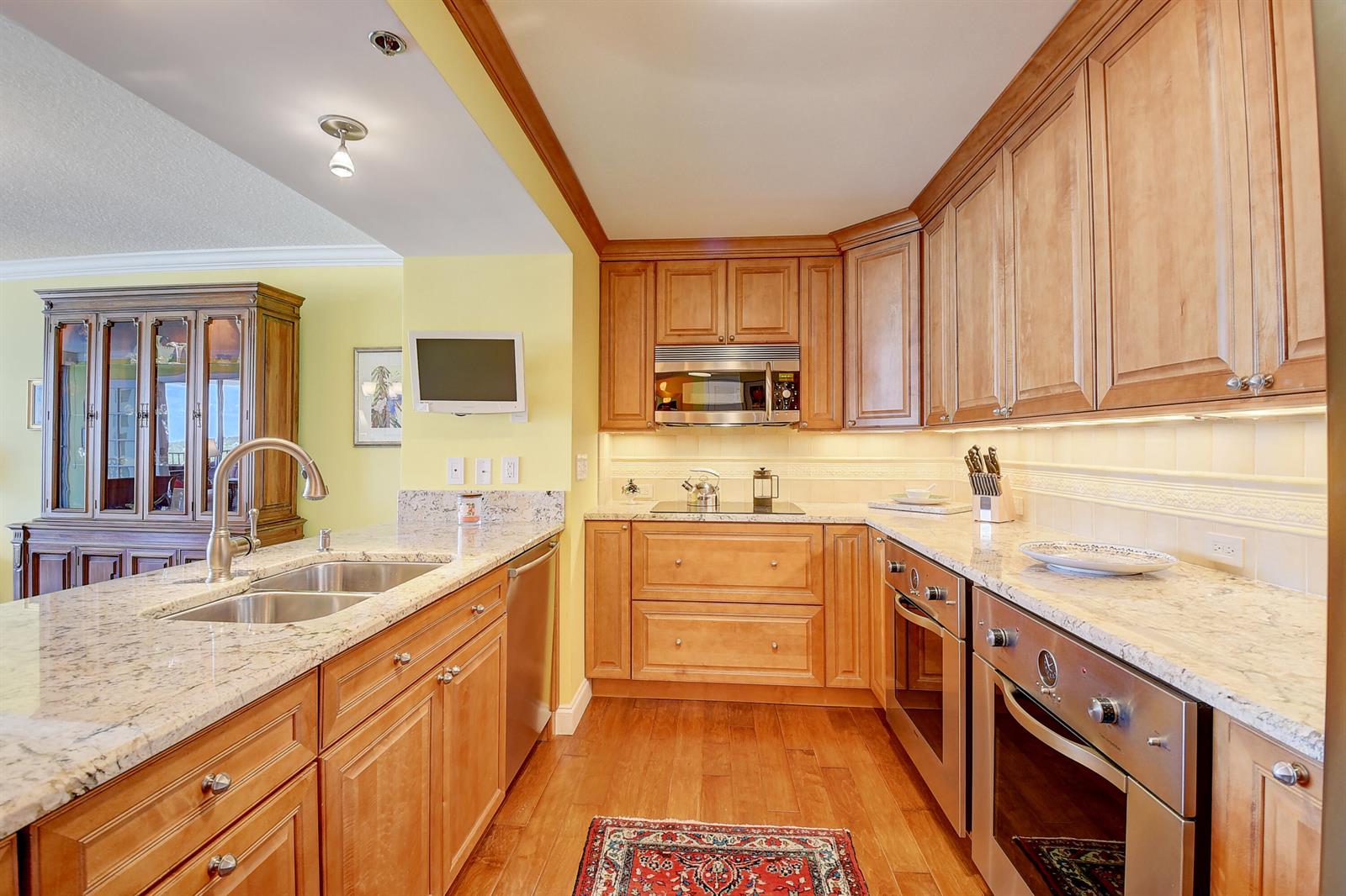 A kitchen with light wood cabinets, granite countertops, stainless steel appliances, and hardwood flooring — 4750 S Ocean Boulevard # 702, Highland Beach FL 33487, HIGHLAND BEACH, FL