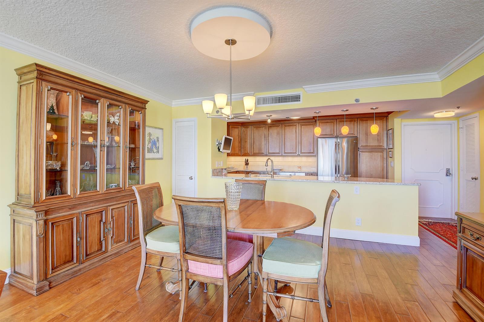 A dining area with a wooden table and hutch opens to a kitchen with cabinets — 4750 S Ocean Boulevard # 702, Highland Beach FL 33487, HIGHLAND BEACH, FL