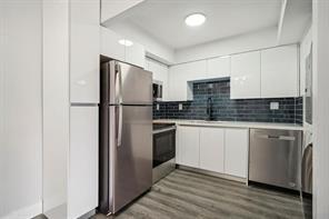A modern kitchen features white cabinets, stainless steel appliances, and a dark blue tiled backsplash — 3244 NW 84th Avenue, Sunrise FL 33351, SUNRISE, FL
