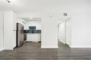 A modern kitchen with white cabinets and dark tile backsplash viewed from a living area — 3244 NW 84th Avenue, Sunrise FL 33351, SUNRISE, FL