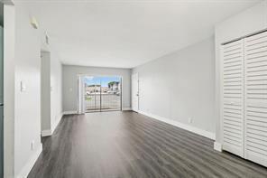 An empty living room features gray wood-look flooring, light gray walls, and white louvered closet doors — 3244 NW 84th Avenue, Sunrise FL 33351, SUNRISE, FL