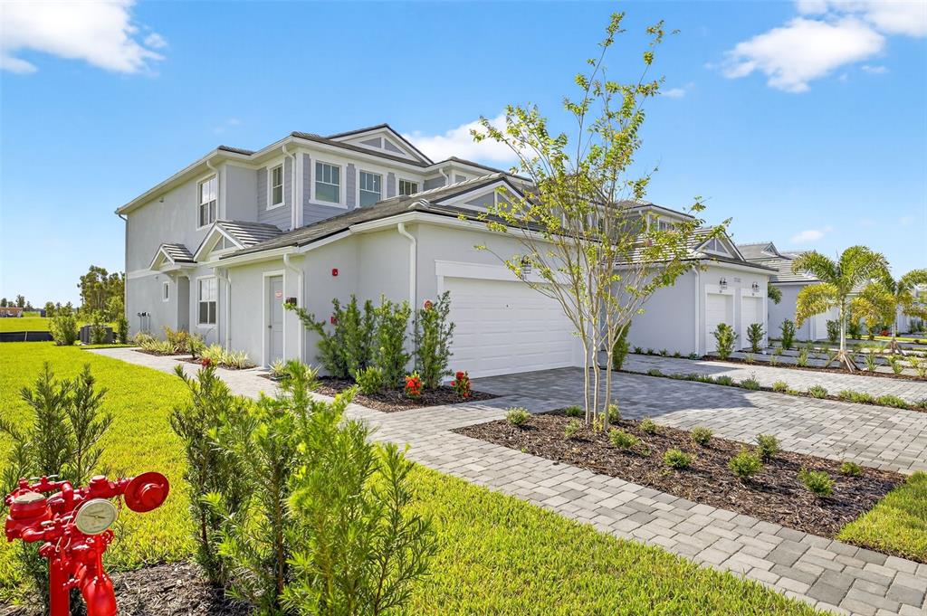A two-story townhouse with a light gray exterior, a paved driveway, and a red fire hydrant — 17420 MOONFLOWER DRIVE UNIT 201, VENICE, FL