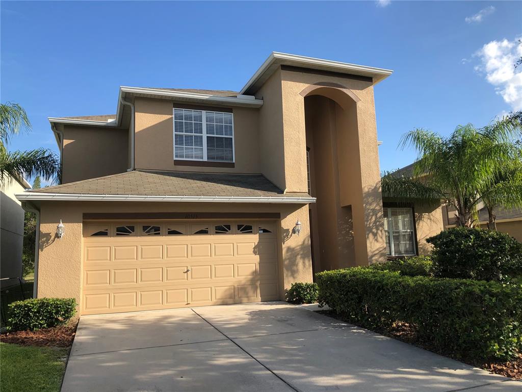 A two-story tan stucco house features a two-car garage and a recessed front entryway — 10515 CORAL KEY AVENUE, TAMPA, FL