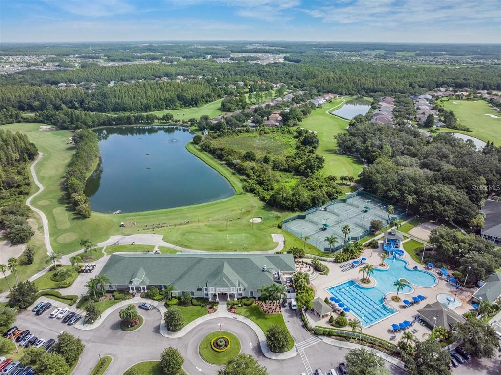 An aerial view shows a clubhouse, swimming pool, tennis courts, and a lake on a golf course — 10515 CORAL KEY AVENUE, TAMPA, FL