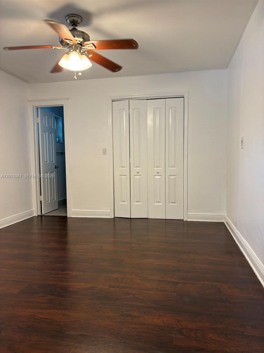 A bedroom features dark wood flooring, a ceiling fan, and a white bi-fold closet door — HOLLYWOOD, FL