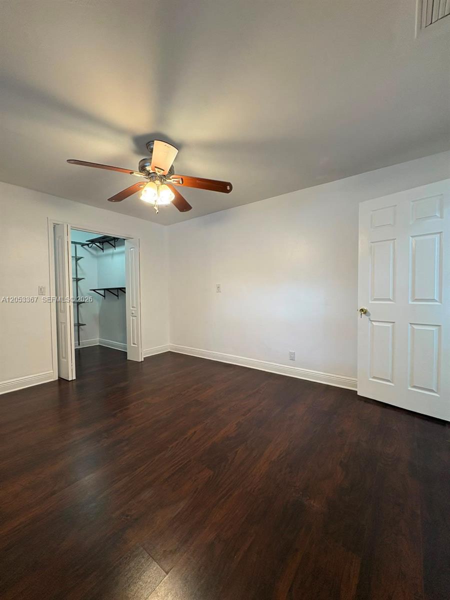 A bedroom features dark wood-look flooring, white walls, a ceiling fan, and an open closet — HOLLYWOOD, FL