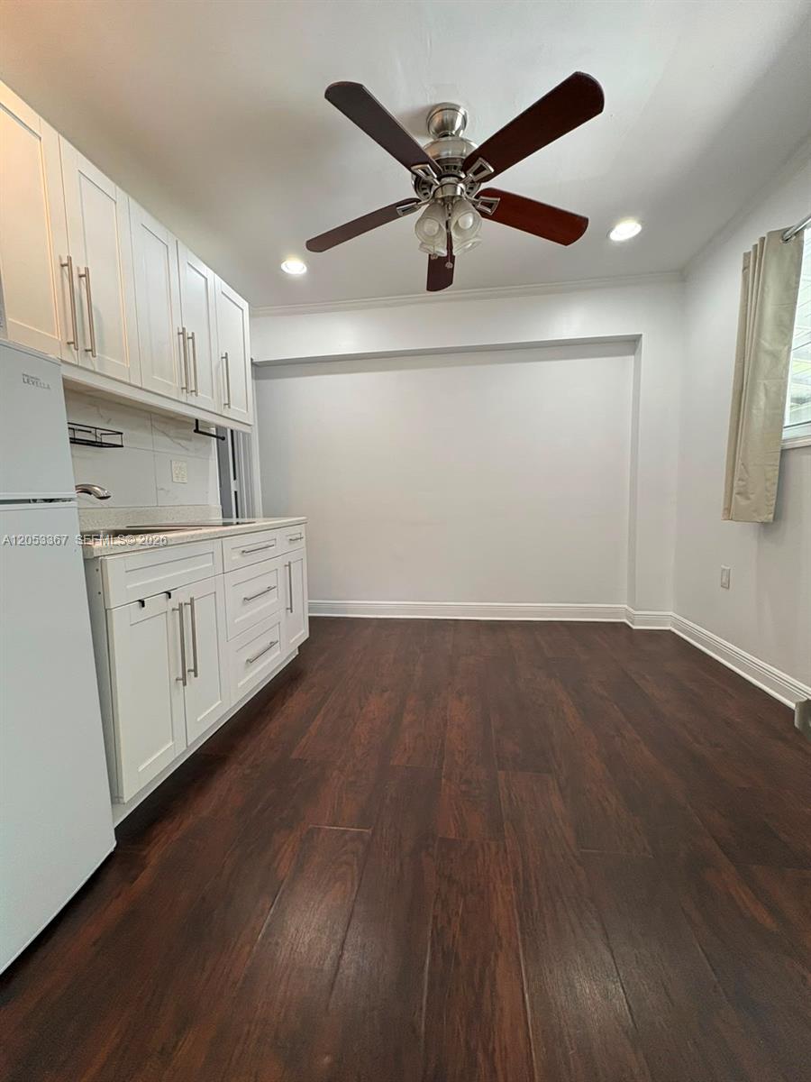 A small kitchen features white cabinets, dark wood flooring, and a ceiling fan — HOLLYWOOD, FL