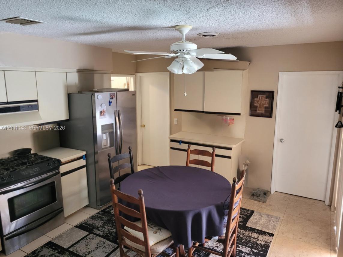A kitchen features light-colored cabinets, stainless steel appliances, and a round dining table — 270 SE 1st Ter, Pompano Beach FL 33060, POMPANO BEACH, FL