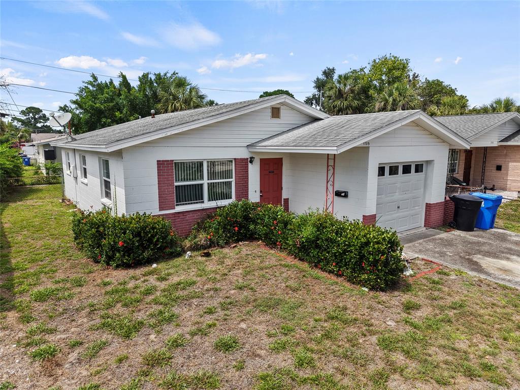 A single-story house with white siding, red brick accents, a red front door, and a garage — 1735 MISSISSIPPI AVENUE NE, ST PETERSBURG, FL