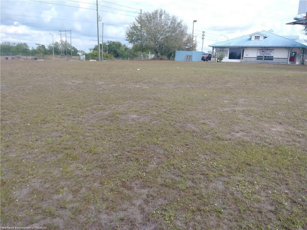 A large, flat, grassy vacant lot sits adjacent to a single-story commercial building — 1503 US 27 S, LAKE PLACID, FL
