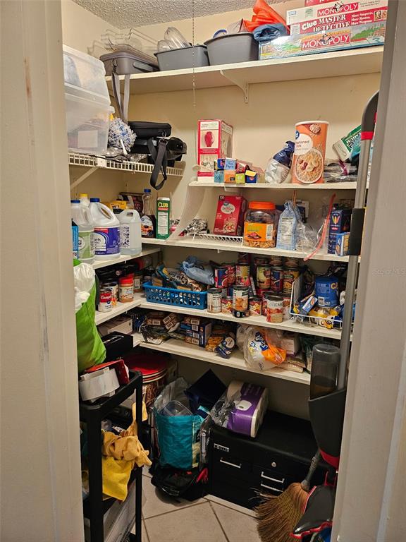 A pantry with multiple white wire shelves filled with various food items and household supplies — 2613 PINE LAKE TER UNIT B, SARASOTA, FL