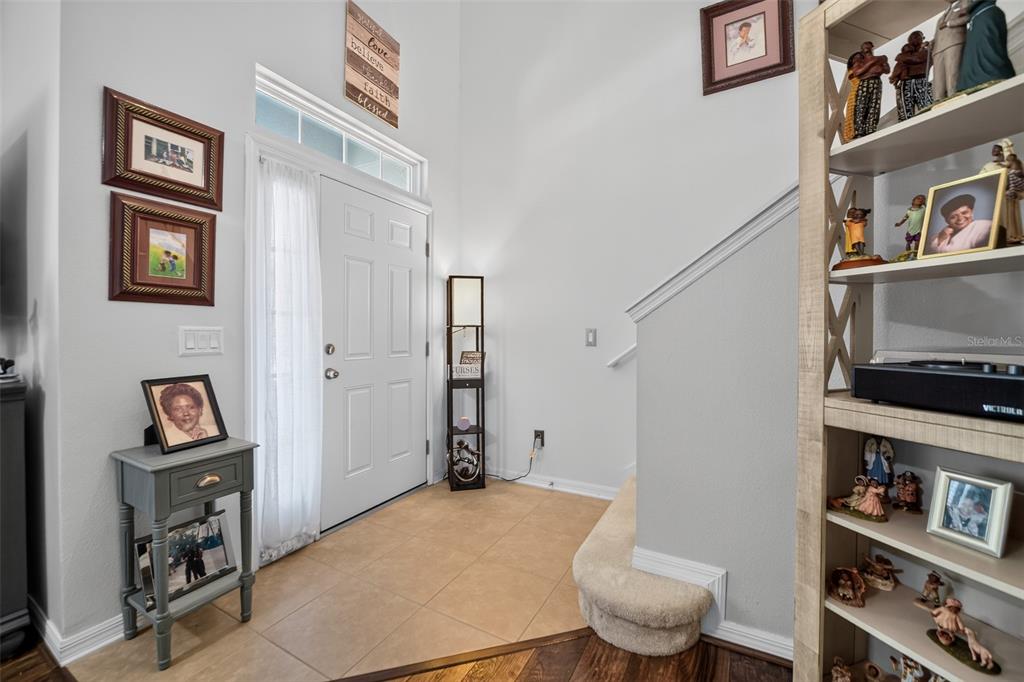 An entryway features a white front door, tiled floor, staircase, and a tall wooden shelving unit — 5863 CYPRESS HILL ROAD, WINTER GARDEN, FL