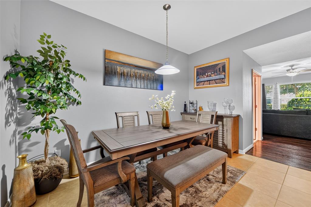 A dining room features a wooden table, chairs, a bench, and a pendant light — 5863 CYPRESS HILL ROAD, WINTER GARDEN, FL